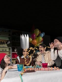 4 Personen sitzen am Tisch und feiern Geburtstag